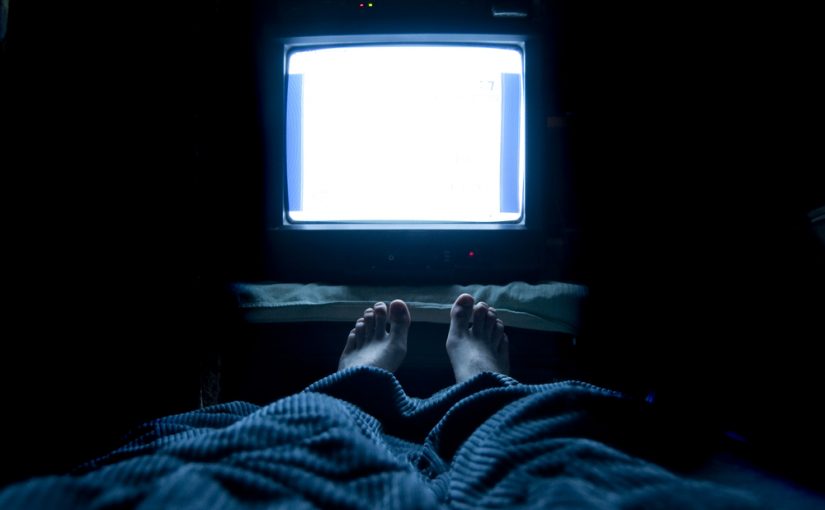 Pessoa assistindo televisão em ambiente escuro